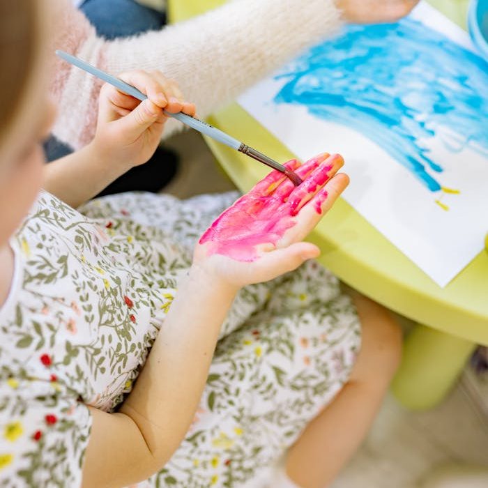 A child engages in a creative painting activity using watercolors indoors.